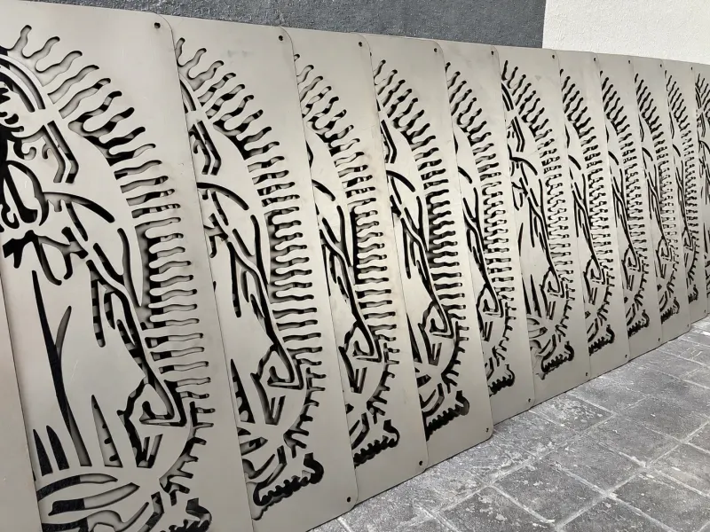 Fila de piezas recortadas en lámina, recargadas en la pared del taller.