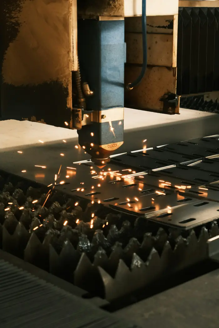 Cabezal de corte láser trabajando sobre una lámina, con chispas.