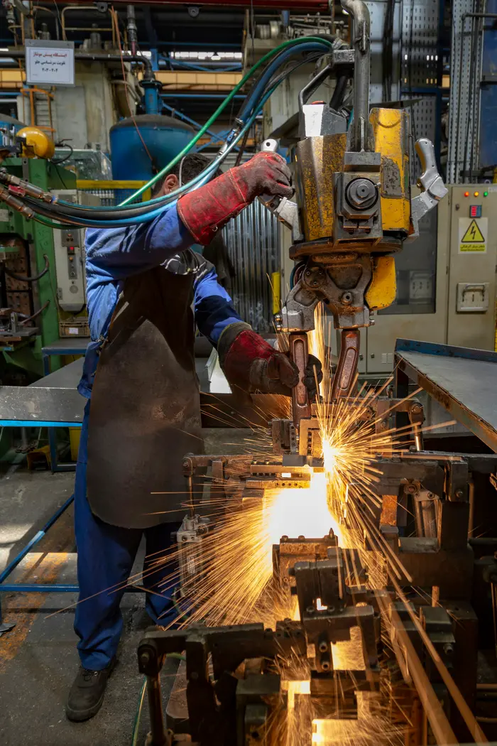 Operario cortando metal con chispas en un taller.