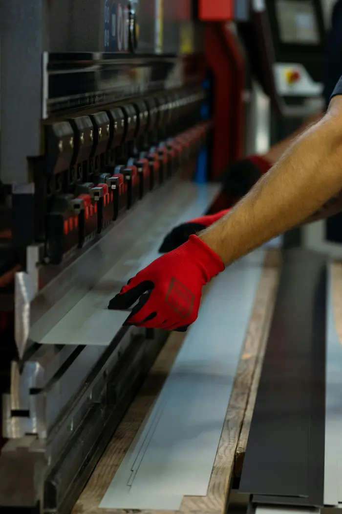 Operario con guantes acomodando una lámina de metal.